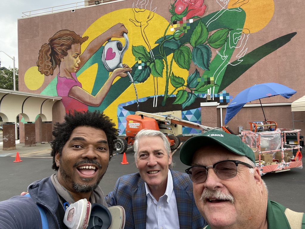 Zulu Painter (left) is greeted by the M&T Bank President and the facilities manager in front of the "Spread Love" mural.